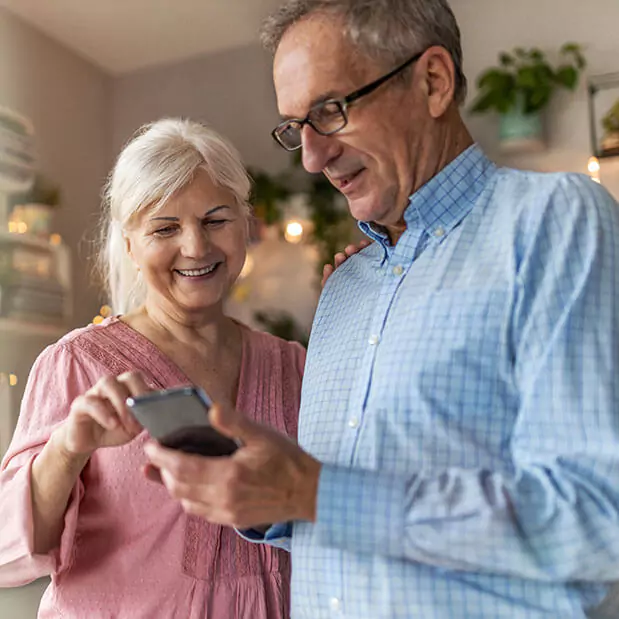 Standing next to each other and looking at a cell phone in his hand, a man and woman smile. Clarkson Pennington Law disability attorneys can answer questions about getting Social Security Disability benefits.