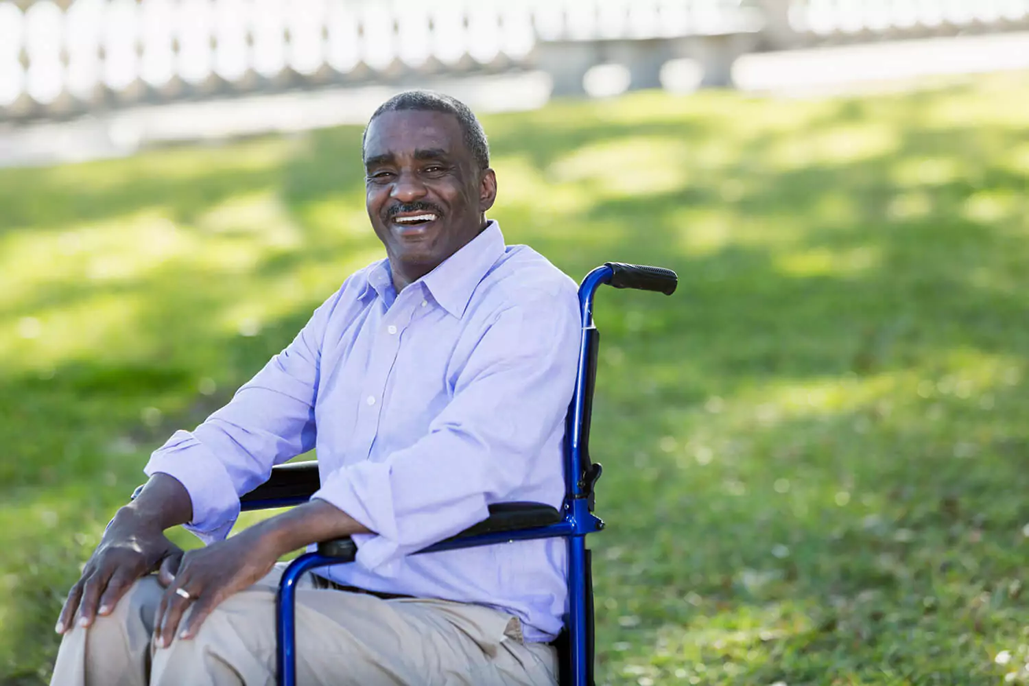 Sitting in a wheelchair in a park, a man smiles for the camera. The Alabama disability lawyers at Clarkson Pennington Law can help you get SSI benefits.