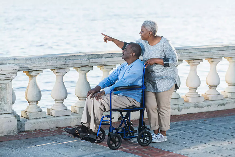 While a man looks over a body of water from his wheelchair, a woman he's with points at something in the distance. Clarkson Pennington Law disability attorneys can answer questions about getting Social Security Disability benefits.